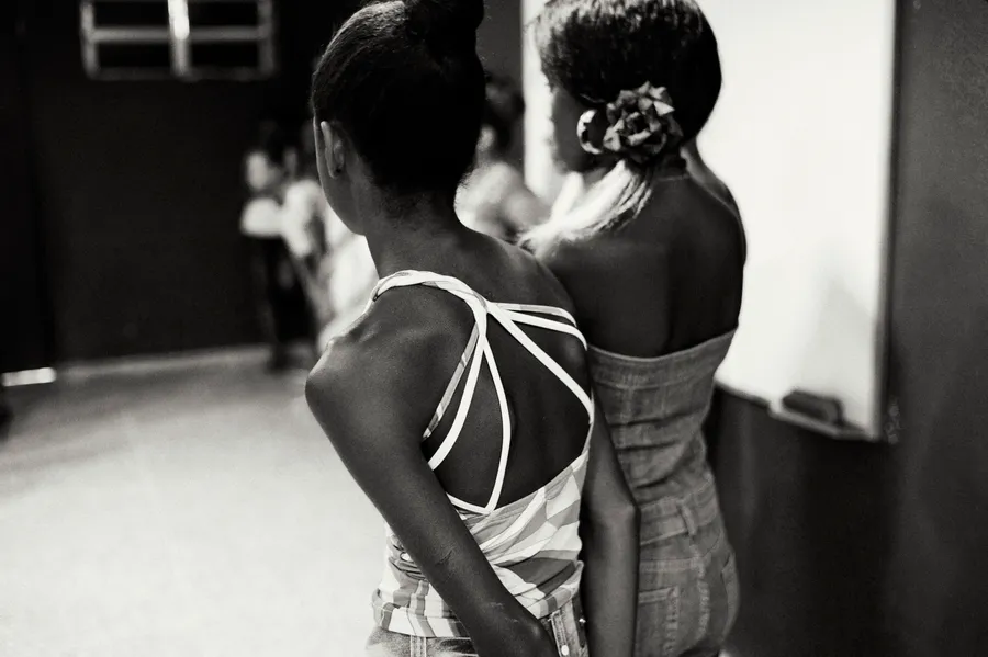Deux jeunes femmes vues de dos, en robe bustier, debout dans une salle, noir et blanc
