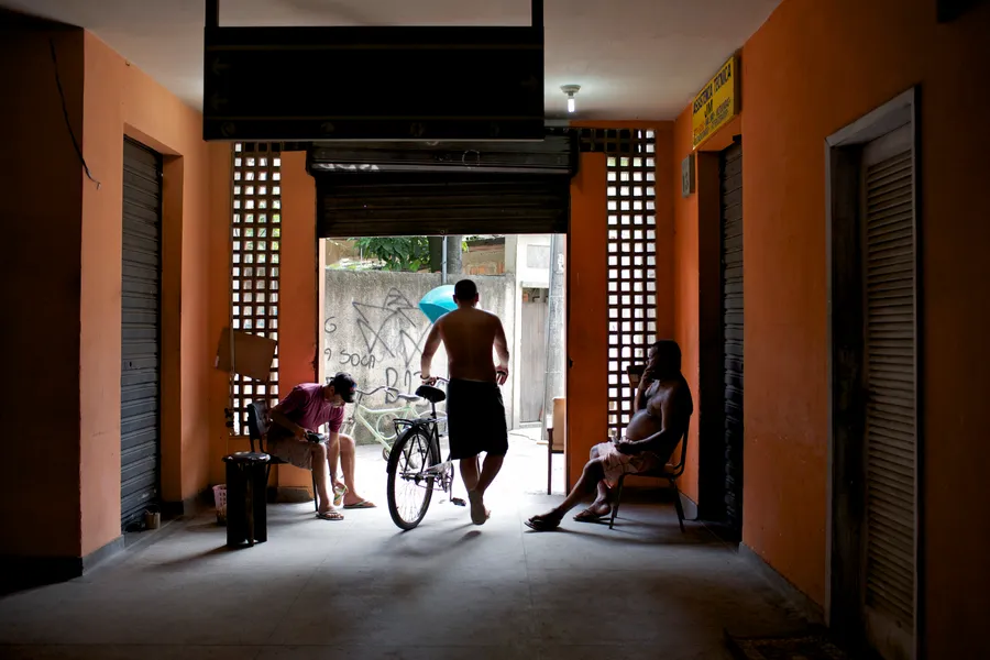 Hommes assis et marchant sous le passage couvert d'un immeuble aux murs orange